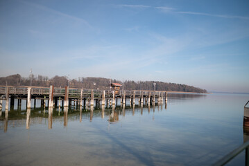 Fototapeta premium Wooden pier at Chiemsee, Bavaria, Germany. Sunny day, Bavarian Alps in the background. Lake