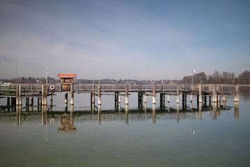 Fototapeta premium Wooden pier at Chiemsee, Bavaria, Germany. Sunny day, Bavarian Alps in the background. Lake