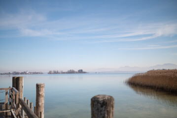Obraz premium Wooden pier at Chiemsee, Bavaria, Germany. Sunny day, Bavarian Alps in the background. Lake