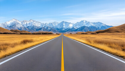 Naklejka premium Asphalt road vanishing into snow-capped mountains under a clear blue sky, flanked by autumnal grasslands