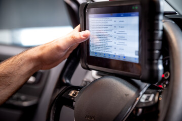 Un técnico automotriz utilizando una herramienta de diagnóstico montada en el volante dentro del...