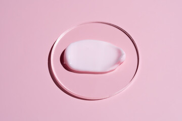 pink cosmetic face cream or body lotion moisturizer strokes on pastel pink background in petri dish. Hygiene, skincare product with creamy texture. Beauty face creme smear swatch on color background