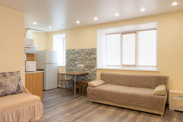 Apartment interior. Living room combined with kitchen. Household appliances and furniture in the living space. There are sofas in the living room. There is a refrigerator and a table in the kitchen.