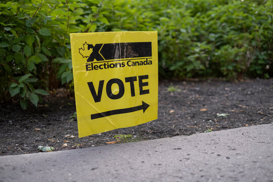Sign elections: Canada vote with official logo and maple leaf in front of the voting office during early federal elections.