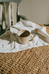 A white coffee cup sits on a napkin on a brown rug. The napkin is folded neatly and the cup is placed in the center of the napkin. Concept of calm and relaxation, as the cup