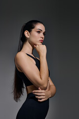 Fototapeta premium Sporty young woman in a thoughtful pose emphasizing strength and elegance in a sleek outfit