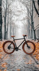 Fototapeta premium Sleek black bicycle on cobblestone path, autumn leaves, misty trees