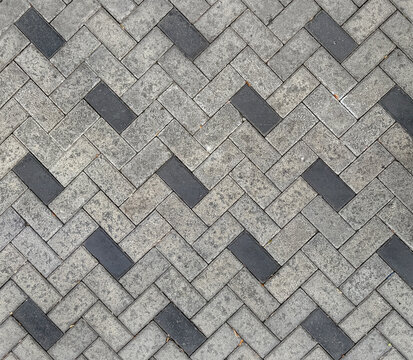 Outdoor grey and white paving stone in chevron and diagonal pattern. For flooring in public place such as pavement, sidewalk, footpath, or promenade. Seamless paving stone background texture.
