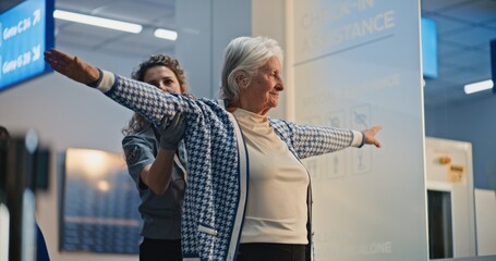Security Checkpoint: Female TSA Officer Checking Elderly Woman in Airport Terminal, Woman Getting...