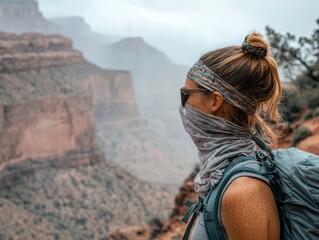 Fototapeta premium person wearing sunglasses and bandana while hiking in mountainous landscape, showcasing sense of adventure and protection against dust. misty background adds dramatic touch to scene