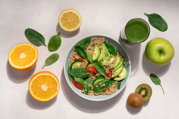 Quinoa spinach avocado salad on light background surrounded by fruits, smoothie and spinach leaves. Healthy food concept
