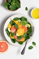 Fresh grapefruit avocado orange spinach salad in bowl. Healthy salad on gray background top view