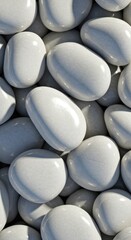 Smooth, polished gray pebbles closely stacked, reflecting soft light with a glossy texture 03