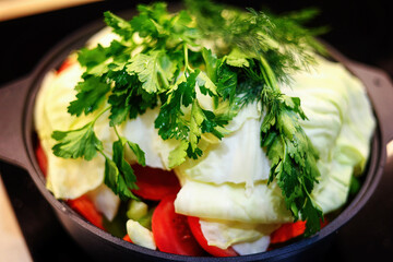 Vegetables and herbs are cooked on the stove in close-up. Meal