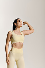 Fototapeta premium Young beautiful sporty woman flexing her muscles in a dynamic exercise pose indoors