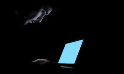 Programmer working late at night on laptop in dark room