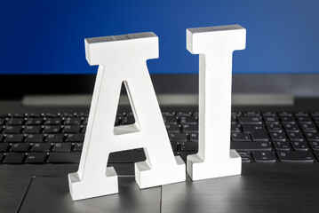  Letras tridimensionales blancas con el texto AI sobre el teclado de un ordenador portátil con la...