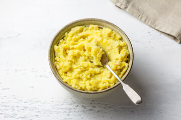 Creamy mashed potatoes in rustic bowl, perfect as a side dish or filling for pastries on a light gray background
