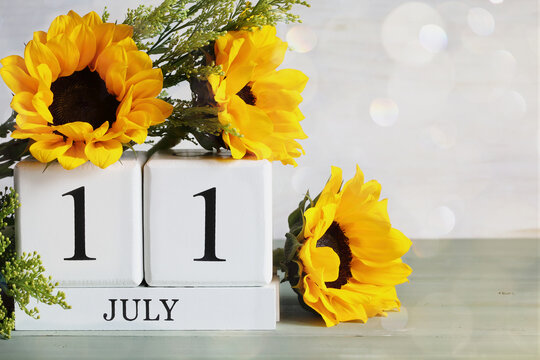 World Population Day.  White wood calendar blocks with the date July 11th and beautiful sunflower bouquet with bokeh. Selective focus with blurred background. 