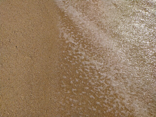 Fine golden sand covering a beach during a sunny day with clear skies, creating a serene and tranquil atmosphere for relaxation