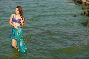 Young brunette woman in bikini standing in the water at the sea