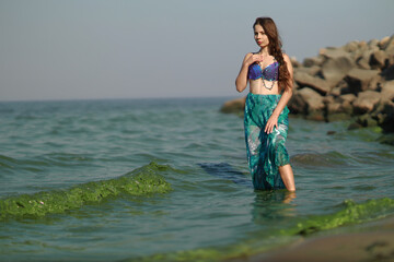 Young brunette woman in bikini standing in the water at the sea