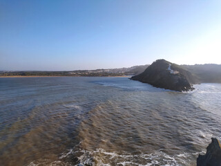 Coastal cliff view of rough waves crashing against the rocks in the afternoon sunlight at a scenic seaside location