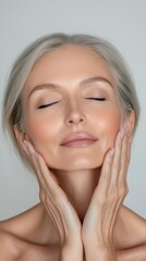 Woman with eyes closed and hands supporting her face looks relaxed and peaceful. Suitable for websites about health, wellbeing and spa treatments.