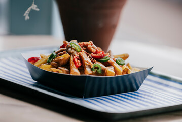 A tray of food with a black container and a blue and white tablecloth