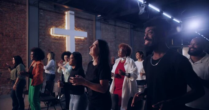 Multicultural congregation clapping and singing in church, illuminated cross in background, vibrant moment of shared faith, joy, and unity during worship