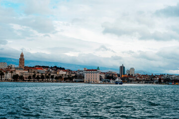 Panoramic view of coastal city with historic buildings, modern architecture and mountains under cloudy sky. Split, Croatia