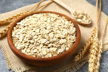 Composition with oatmeal flakes on gray background. Cooking breakfast