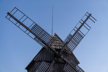 old wooden windmill in a field against a blue sky. windmill propeller
