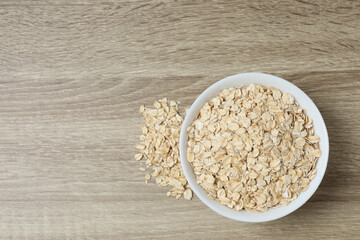 Composition with oatmeal flakes on wooden background. Cooking breakfast
