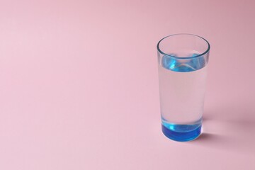 Glass of water on color background