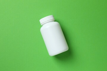 White bottle on green background, top view