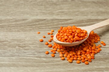 Red lentils in a spoon on a wooden background