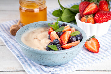 Cream of Wheat semolina porridge with fresh summer berry. Portion of breakfast whole grain creme de  semolina with dairy milk, strawberry, blueberry and honey