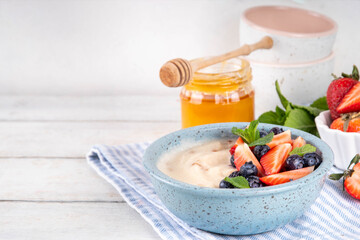 Cream of Wheat semolina porridge with fresh summer berry. Portion of breakfast whole grain creme de  semolina with dairy milk, strawberry, blueberry and honey