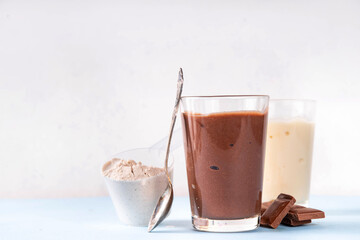 Quick and simple protein pudding. Healthy summer cold dessert. Three glasses with vanilla, chocolate and berry protein pudding, with chocolate slices, fresh strawberry, blueberry, protein powder scoop