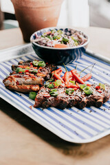 A plate of ribs and a bowl of coleslaw sit on a table