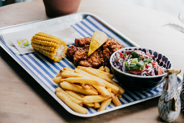 A plate of food with a bowl of coleslaw and a piece of corn