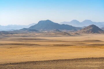 Fototapeta premium A vast desert landscape with mountain ranges under a blue sky