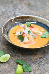 A flavorful and spicy Thai Tom Yum Goong soup with shrimp, rice noodles, and a rich coconut milk broth. Garnished with fresh cilantro and red chili, 
