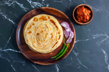Crispy, flaky laccha paratha served hot with tangy pickle, fresh onion slices, and spicy green chili for a perfect flavor burst.