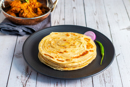 Crispy, flaky laccha paratha served hot with tangy pickle, fresh onion slices, and spicy green chili for a perfect flavor burst.