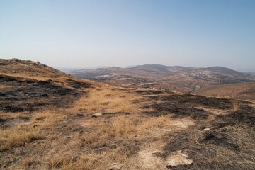 An expansive view of hills with dry grass and blue sky