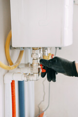 Gloved hand adjusts a valve on industrial equipment, showcasing industrial maintenance work. The...