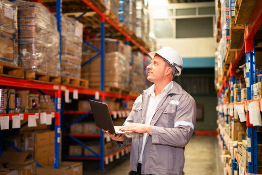 A warehouse manager using a laptop to oversee inventory and ensure efficient operations in a large storage facility.