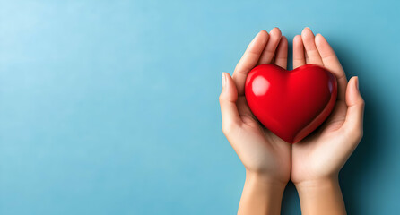 Obraz premium A pair of hands gently holding a vibrant red heart symbolizing love and care on a blue background.